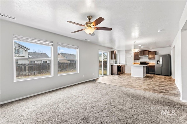 unfurnished living room featuring a textured ceiling, carpet floors, ceiling fan, and baseboards