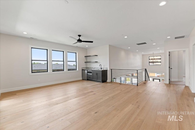 unfurnished living room with ceiling fan, light wood-type flooring, and sink