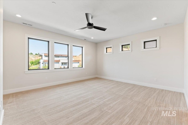 spare room with ceiling fan and light colored carpet