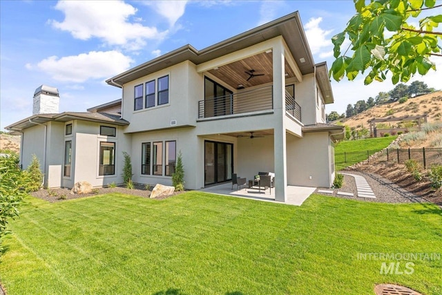 rear view of property with a yard, a patio area, ceiling fan, and a balcony