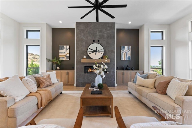 living room featuring ceiling fan, light hardwood / wood-style floors, a fireplace, and a wealth of natural light