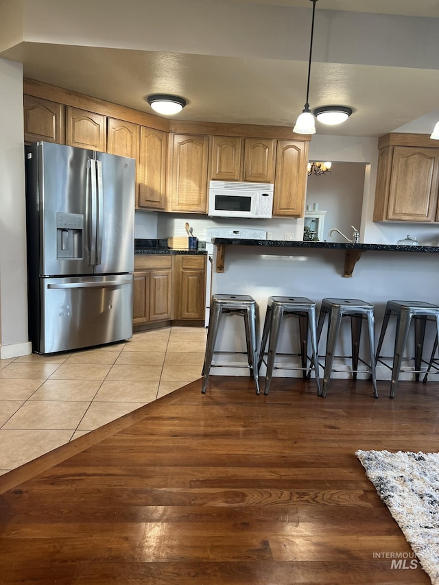140 W Valley Rd, Hagerman, ID 83332 - kitchen with stainless steel fridge with ice dispenser, white microwave, a kitchen bar, and light wood-style flooring