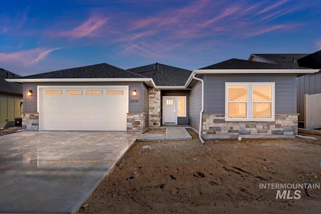 view of front facade featuring a garage, stone siding, a shingled roof, and concrete driveway