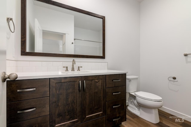 bathroom featuring wood-type flooring, vanity, toilet, and decorative backsplash