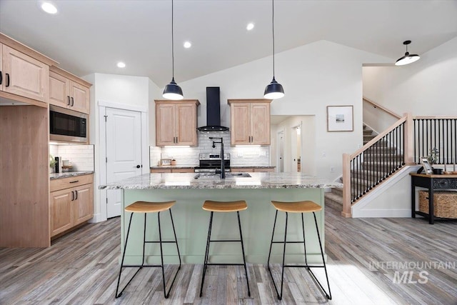 kitchen with built in microwave, wall chimney range hood, pendant lighting, and light brown cabinets