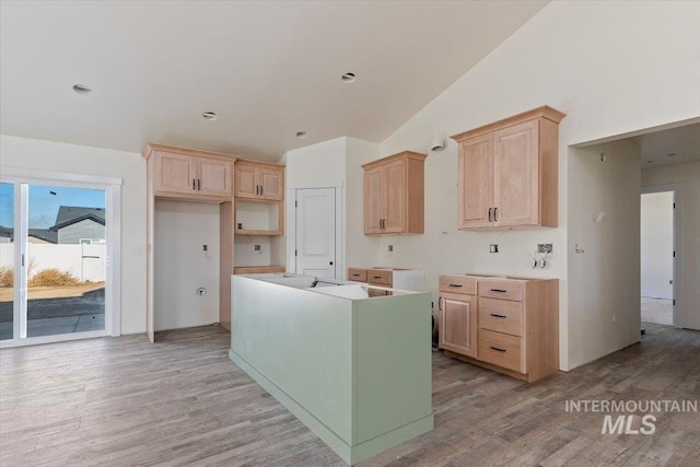 kitchen with lofted ceiling, light wood-type flooring, and light brown cabinets