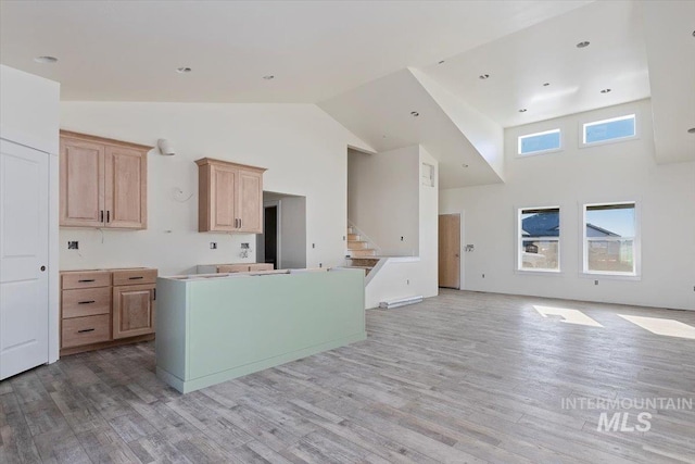 kitchen featuring light brown cabinetry, high vaulted ceiling, and light hardwood / wood-style floors