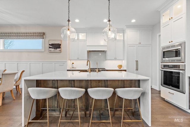 kitchen featuring white cabinetry, an island with sink, dark hardwood / wood-style floors, and appliances with stainless steel finishes