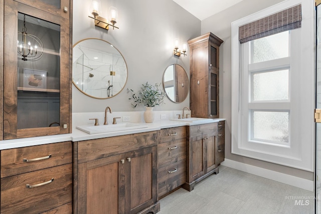bathroom featuring a shower, vanity, an inviting chandelier, and a healthy amount of sunlight
