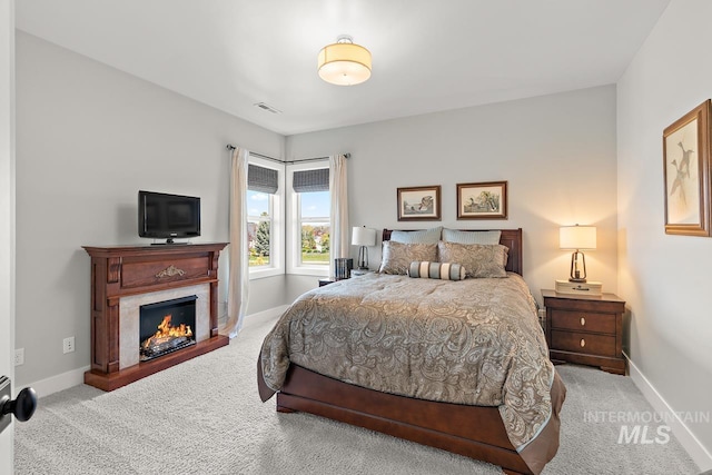 bedroom featuring a premium fireplace and light carpet