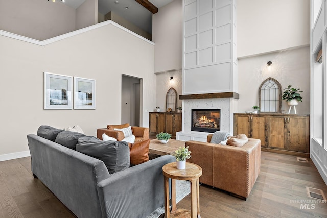living room featuring beamed ceiling, wood-type flooring, and a towering ceiling