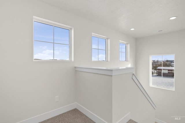 unfurnished room with a healthy amount of sunlight, carpet flooring, and a textured ceiling