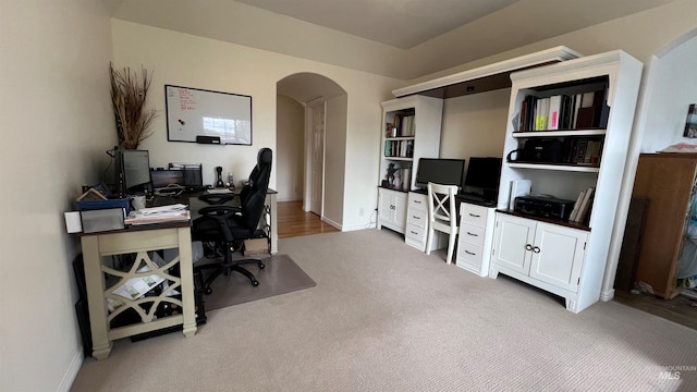 home office with carpet flooring, baseboards, and arched walkways