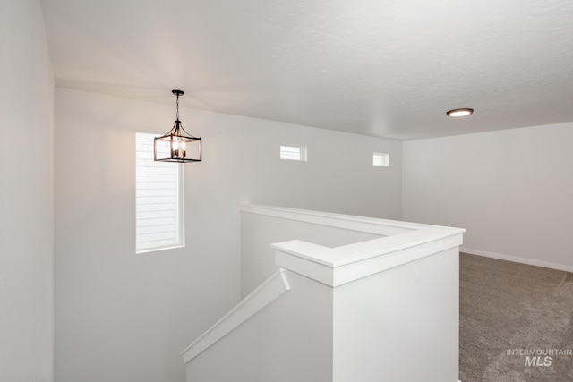 hallway with carpet and an inviting chandelier