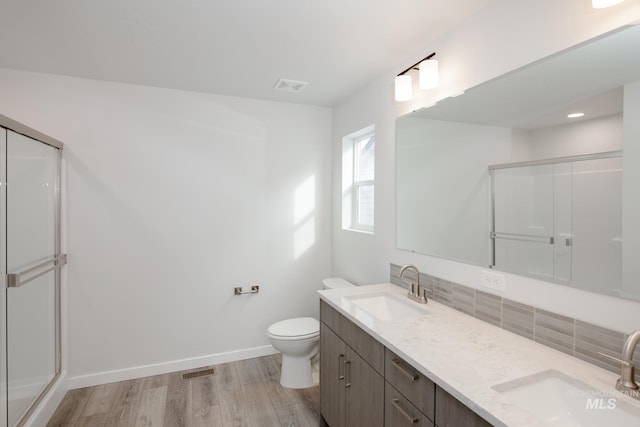 bathroom with wood-type flooring, vanity, toilet, and a shower with shower door