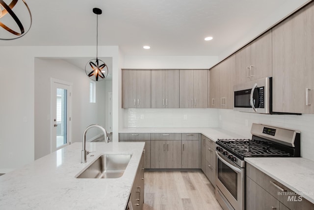 kitchen with light brown cabinets, sink, appliances with stainless steel finishes, light hardwood / wood-style floors, and light stone counters