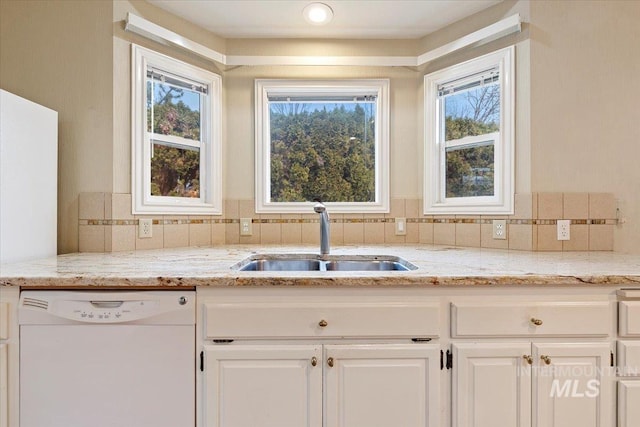 kitchen featuring white cabinets, dishwasher, light stone countertops, a wealth of natural light, and sink