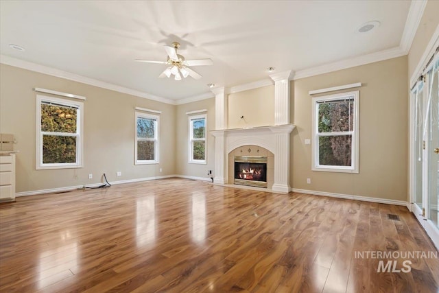 unfurnished living room featuring light hardwood / wood-style floors, ceiling fan, crown molding, and a fireplace