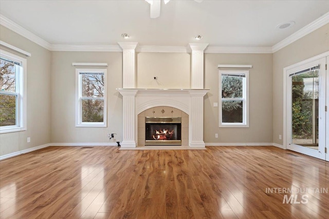 unfurnished living room featuring a tiled fireplace, ornamental molding, and wood-type flooring