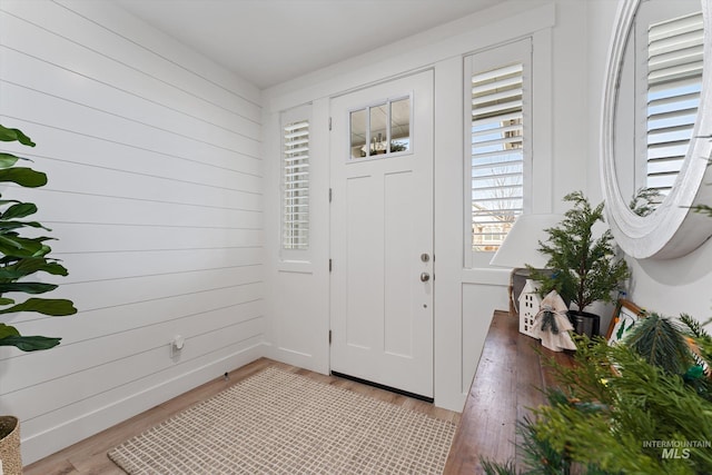 foyer entrance with wooden walls and light wood-type flooring