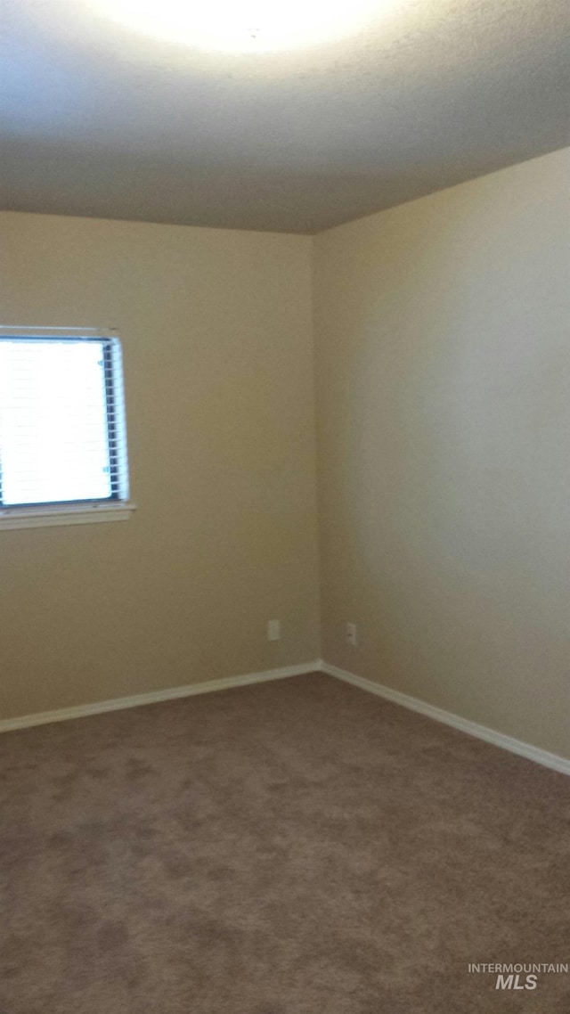 carpeted spare room with baseboards