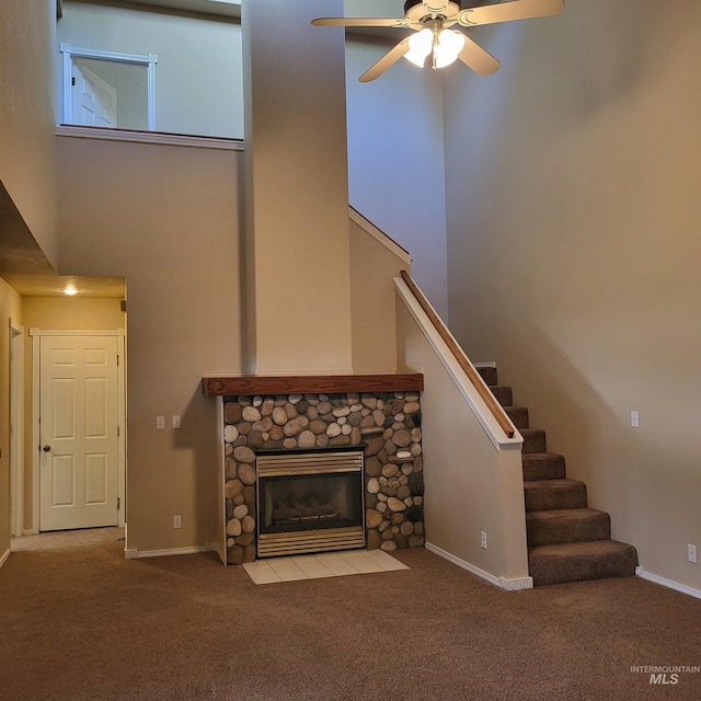 unfurnished living room with stairway, a fireplace, a towering ceiling, and carpet floors