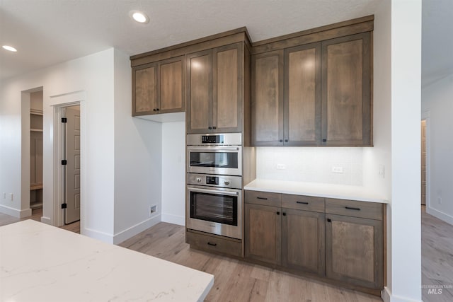 1246 E Rio Chico Dr, Kuna, ID 83634 - kitchen with double oven, light wood-style floors, baseboards, decorative backsplash, and recessed lighting