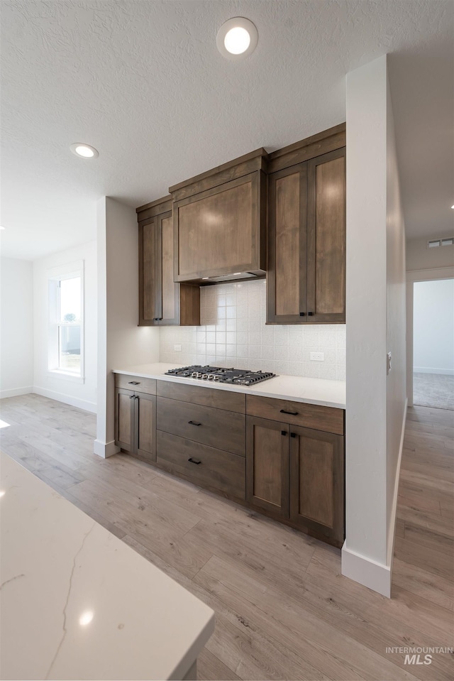 1246 E Rio Chico Dr, Kuna, ID 83634 - kitchen featuring stainless steel gas stovetop, backsplash, light countertops, baseboards, and a textured ceiling
