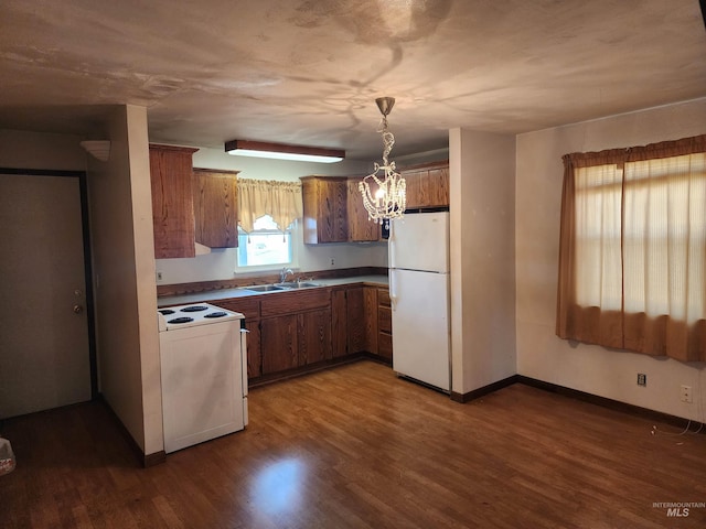 kitchen featuring white appliances, an inviting chandelier, pendant lighting, and dark hardwood / wood-style floors