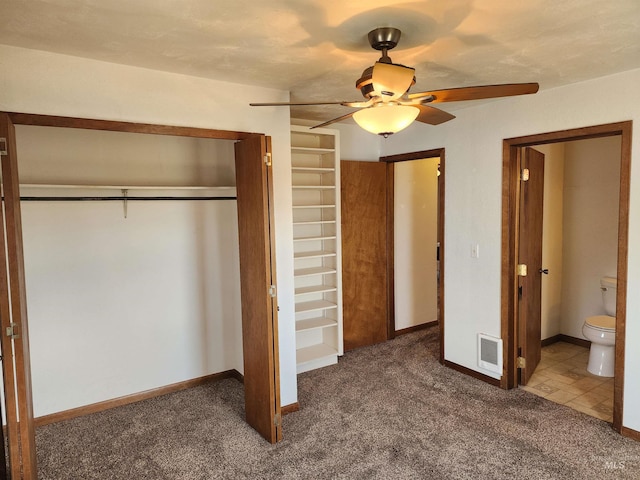 unfurnished bedroom with ensuite bath, carpet, a closet, and ceiling fan