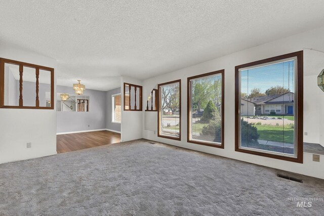 204 Hilldrop St, Caldwell, ID 83605 - unfurnished living room featuring a textured ceiling, carpet floors, visible vents, and an inviting chandelier