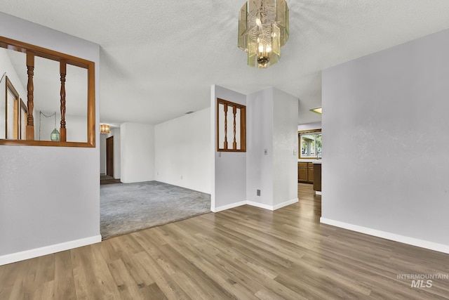 204 Hilldrop St, Caldwell, ID 83605 - unfurnished living room with baseboards, wood finished floors, a textured ceiling, and an inviting chandelier