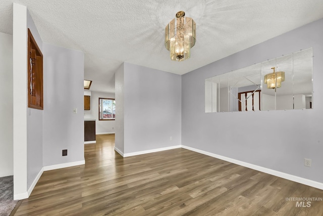 204 Hilldrop St, Caldwell, ID 83605 - spare room with baseboards, wood finished floors, a textured ceiling, and a notable chandelier