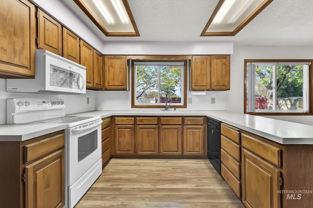 204 Hilldrop St, Caldwell, ID 83605 - kitchen featuring a peninsula, a healthy amount of sunlight, brown cabinets, and white appliances