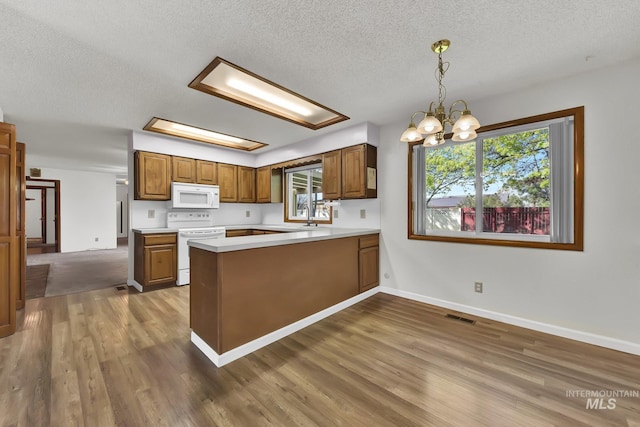 204 Hilldrop St, Caldwell, ID 83605 - kitchen with a peninsula, wood finished floors, visible vents, and white appliances