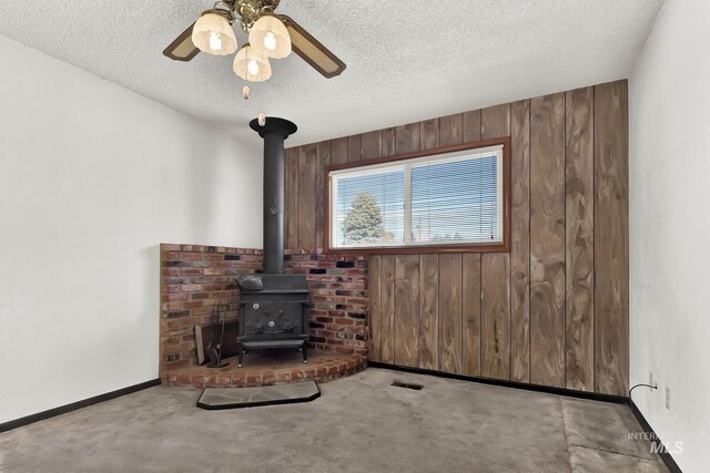 204 Hilldrop St, Caldwell, ID 83605 - unfurnished living room with ceiling fan, wood walls, a textured ceiling, and a wood stove
