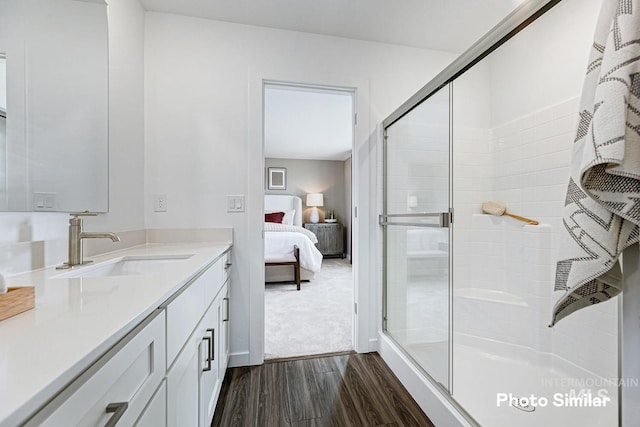 ensuite bathroom featuring wood finished floors, a shower stall, and vanity