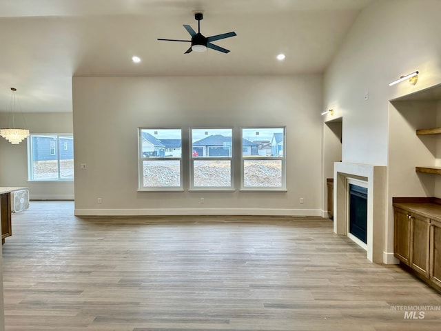 unfurnished living room featuring recessed lighting, light wood-style floors, a fireplace, and ceiling fan with notable chandelier