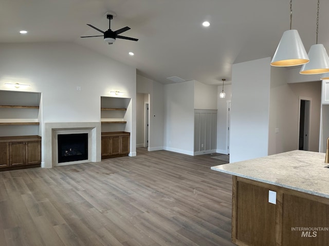 unfurnished living room featuring a ceiling fan, lofted ceiling, a fireplace, and light wood-type flooring