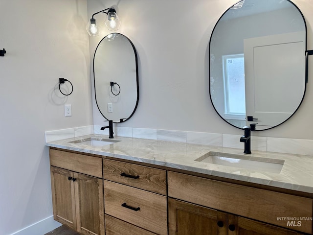 full bath featuring double vanity, baseboards, and a sink