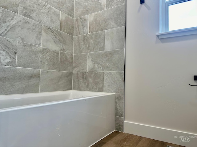 bathroom with wood finished floors and a washtub