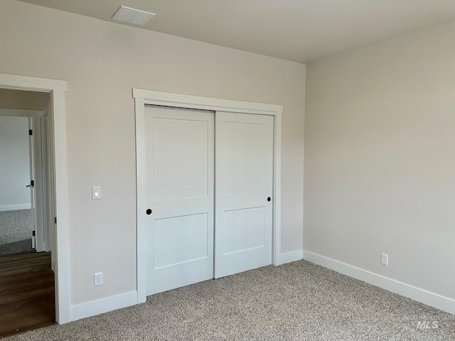 unfurnished bedroom with baseboards, light carpet, a closet, and visible vents