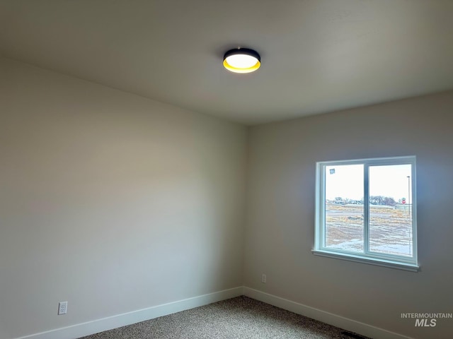 spare room with baseboards and light carpet