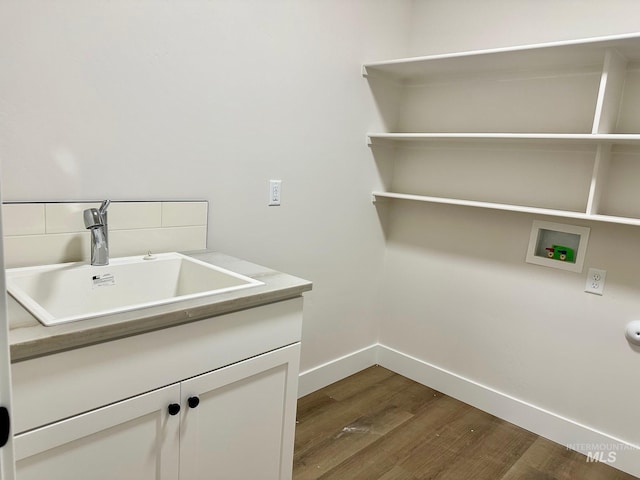 washroom featuring hookup for a washing machine, baseboards, cabinet space, a sink, and dark wood-type flooring