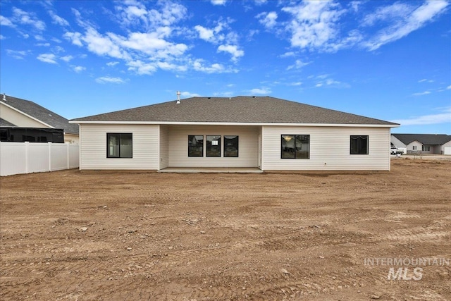 rear view of house with a patio area, fence, and roof with shingles