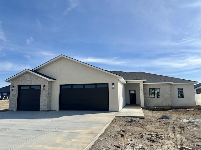 view of front of house featuring an attached garage, stone siding, driveway, and a shingled roof