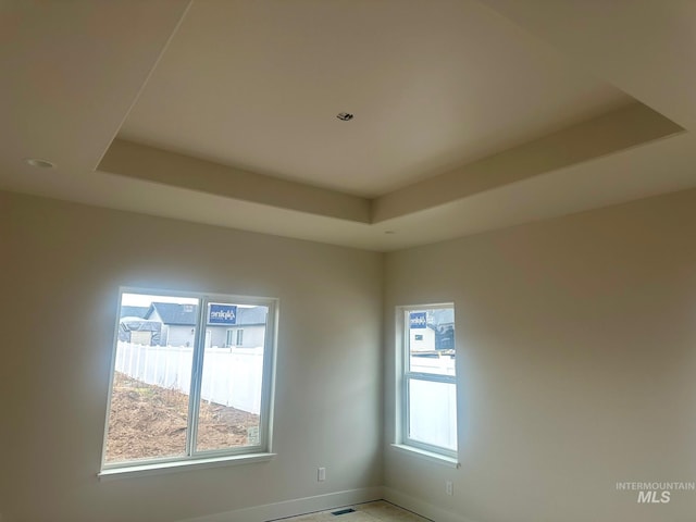 spare room with a raised ceiling and baseboards