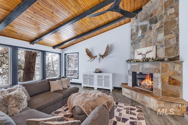 living room with ceiling fan, a stone fireplace, lofted ceiling with beams, hardwood / wood-style floors, and wood ceiling