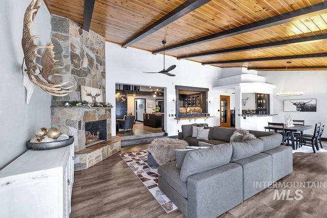 living room featuring beam ceiling, a fireplace, dark hardwood / wood-style flooring, and wood ceiling