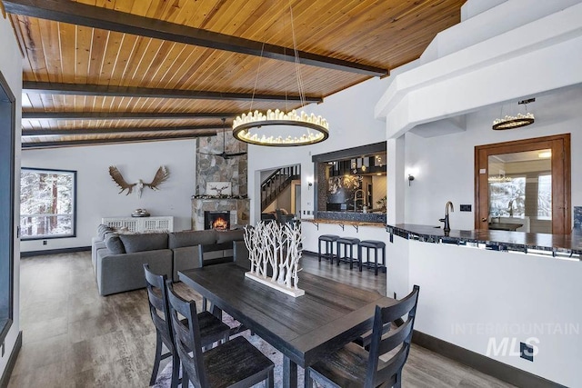 dining space with a fireplace, hardwood / wood-style floors, vaulted ceiling with beams, and wood ceiling